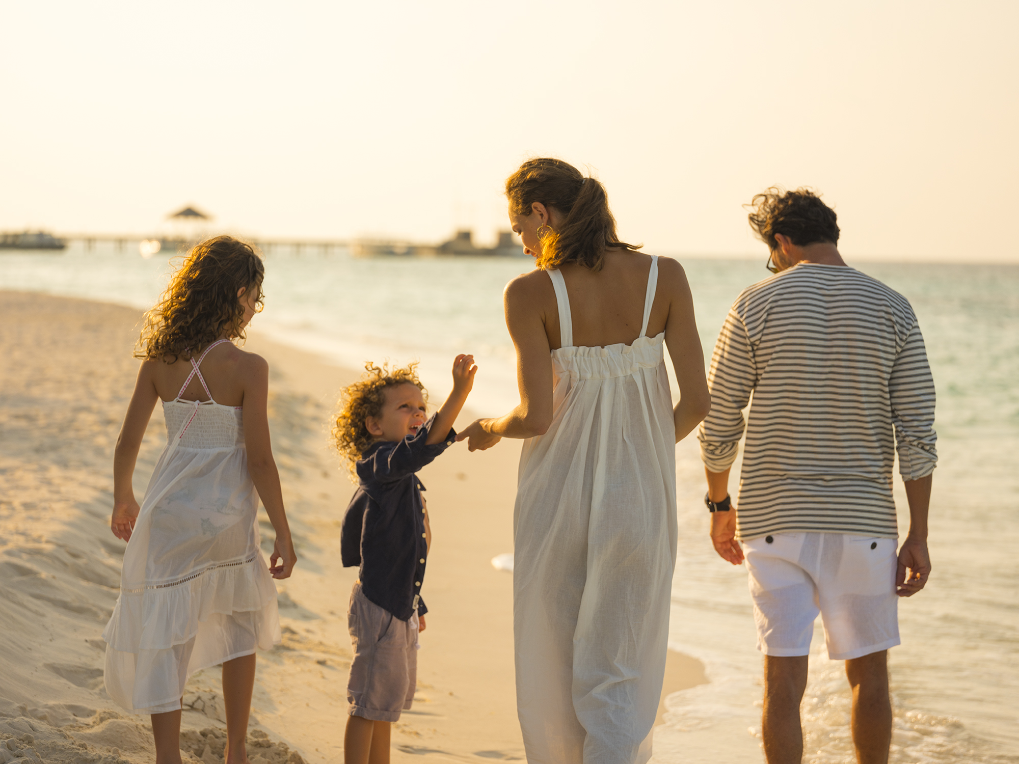 Famiglia sulla spiaggia al tramonto, atmosfera maldiviana